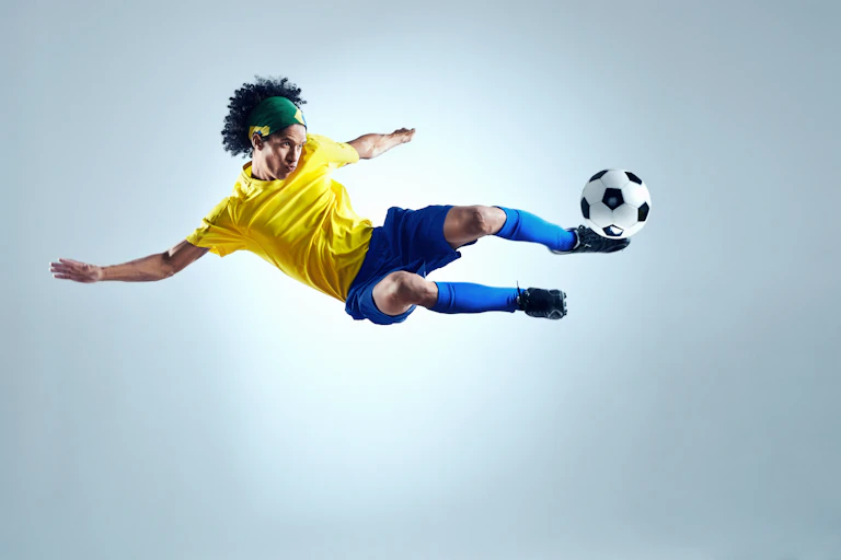 Un futbolista en el aire con la equipación de Brasil chuta un balón.