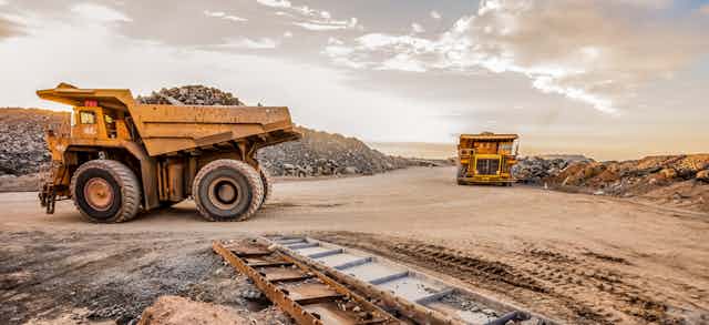 Dump trucks transporting platinum ore for processing at a dusty mining site.