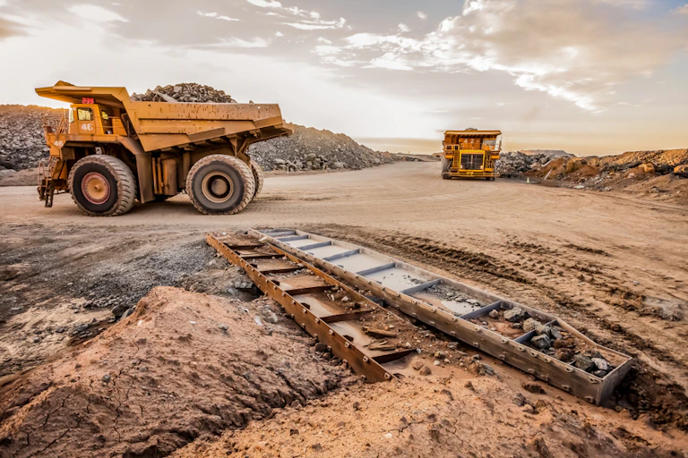 Dump trucks transporting platinum ore for processing at a dusty mining site.
