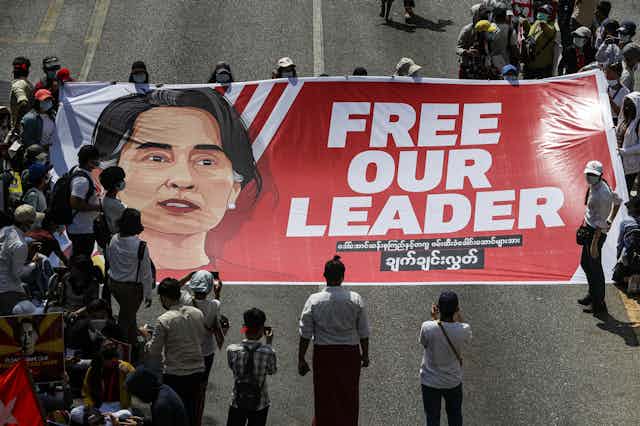 A crowd of protesters holds a large banner demanding the release of Myanmar's de facto leader Aung San Suu Kyi.