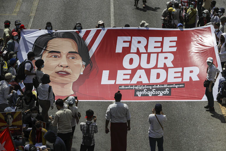 A crowd of protesters holds a large banner demanding the release of Myanmar's de facto leader Aung San Suu Kyi.