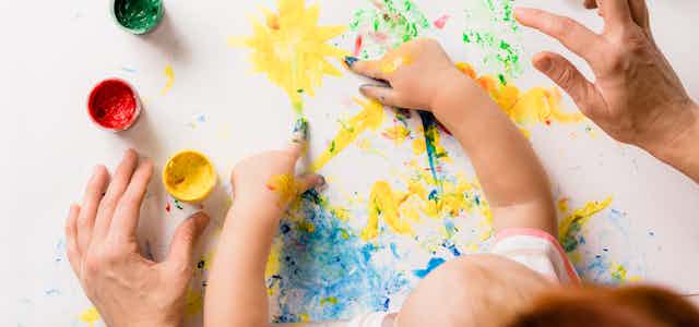 Parents finger painting with their child.