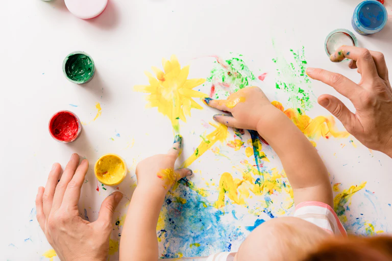 Parents finger painting with their child.