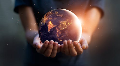 Night-time Earth globe being held by two hands.