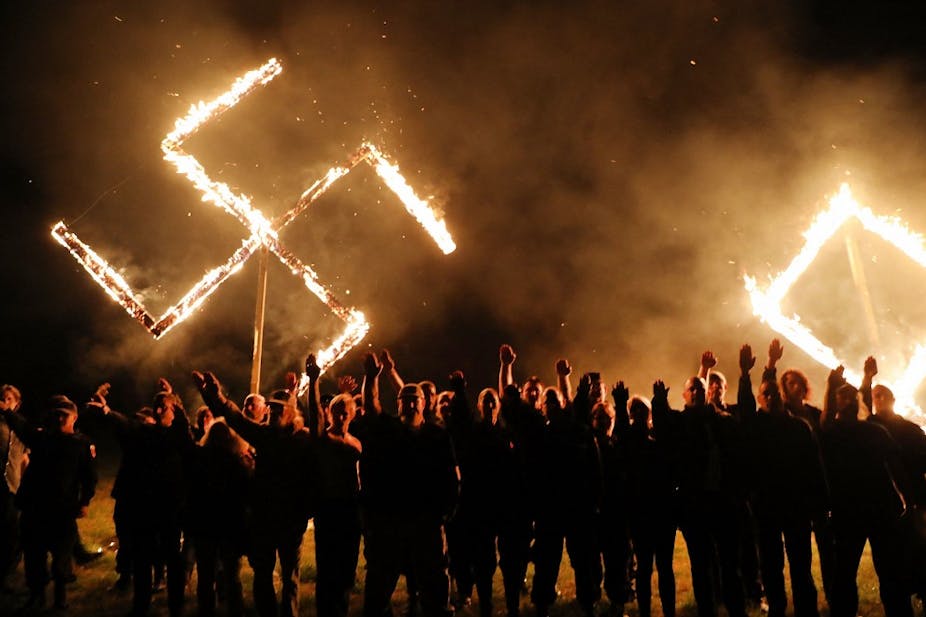 Des néo-nazis devant une croix gammée en feu