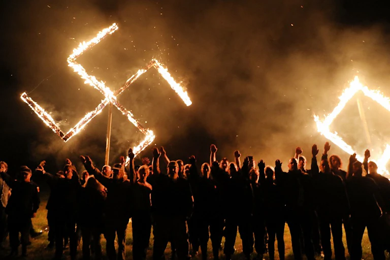 Des néo-nazis devant une croix gammée en feu