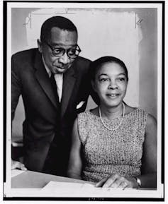 Two Black scientists sit together while conducting their research.