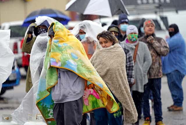 People lined up outdoors wrapped in blankets