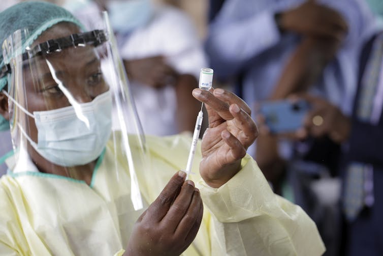 A health worker in Zimbabwe loading a syringe with COVID vaccine fluid