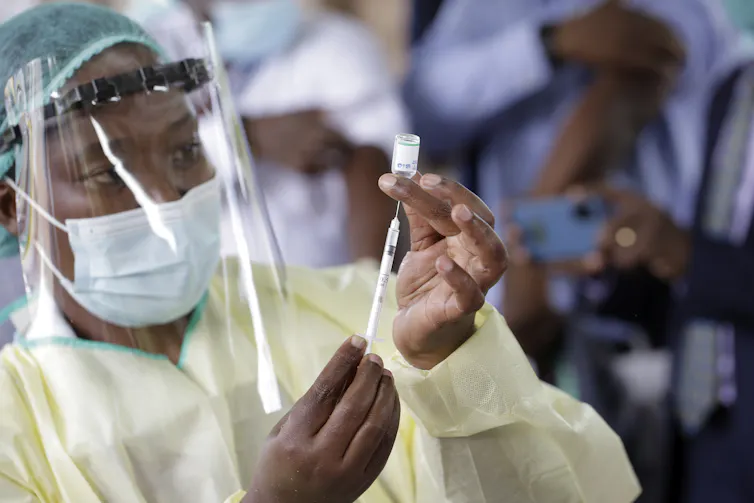 A health worker in Zimbabwe loading a syringe with COVID vaccine fluid
