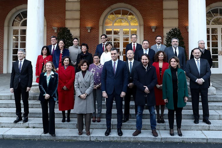 Group photo of Spanish cabinet standing on white steps with Sanchez in middle, surrounded by a gender-diverse group
