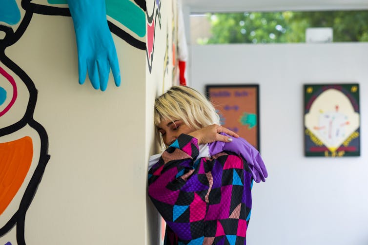 Person in gallery getting hug from rubber gloves on wall