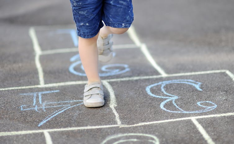 Kid's feet on hopscotch grid.