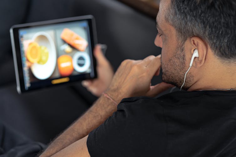 Man watches a cooking video on his tablet.