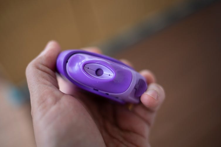 A person holding a purple steroid inhaler