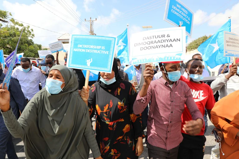 Marching demonstrators wave placards.