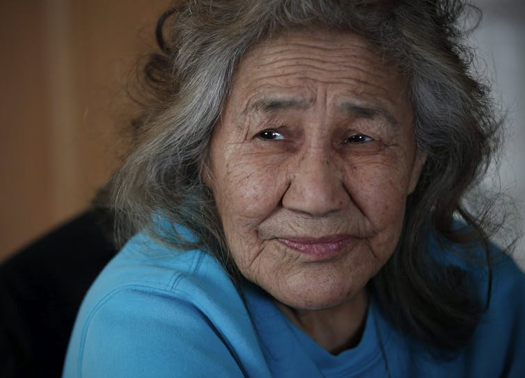 Close-up of an Indigenous woman with grey hair in a blue shirt