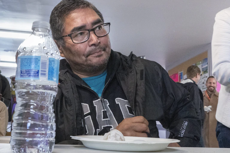 Chief Rudy Turtle sitting at a table with a water bottle and an empty plate in the foreground.