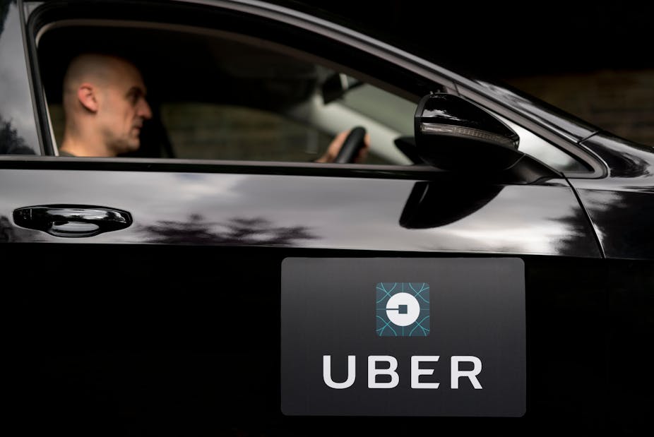 Man driving black car with Uber logo.