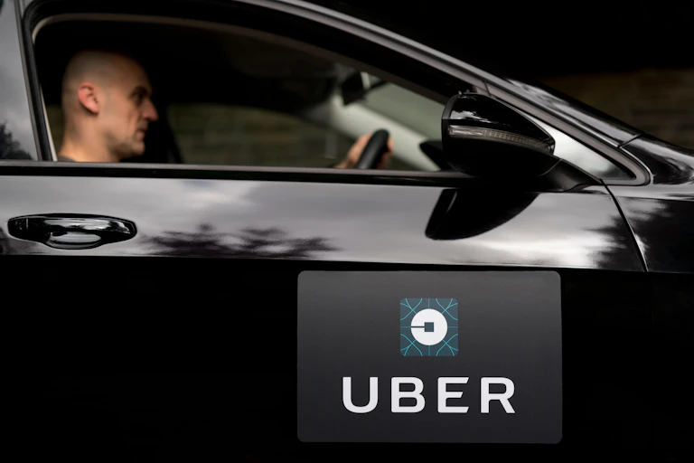 Man driving black car with Uber logo.