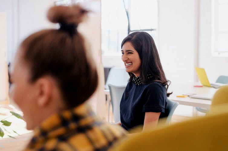 A woman smiles in an office setting.