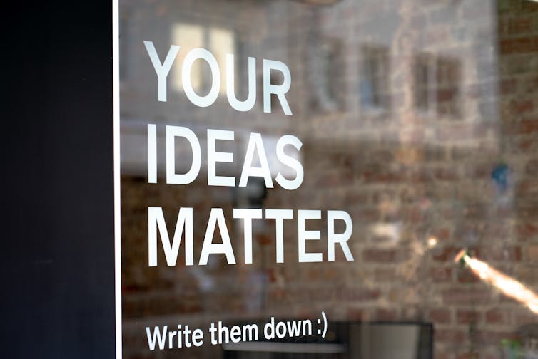A sign reads Your Ideas Matter on a glass office door.