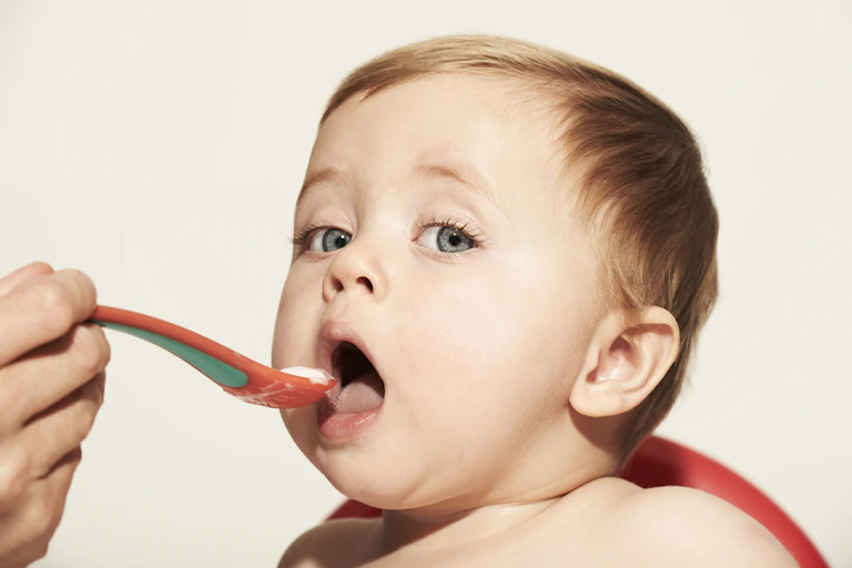 A baby being fed soft food with a spoon.