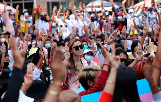 Anti-coup protesters flash the three-fingered salute during a rally