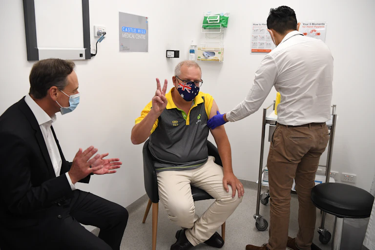 Scott Morrison receives the pfizer vaccine, while giving a "V" sign