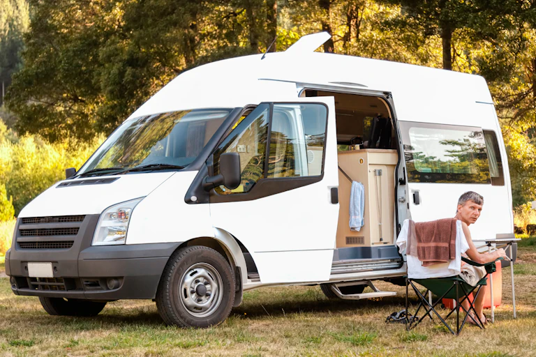 A man sitting outside his camper van.