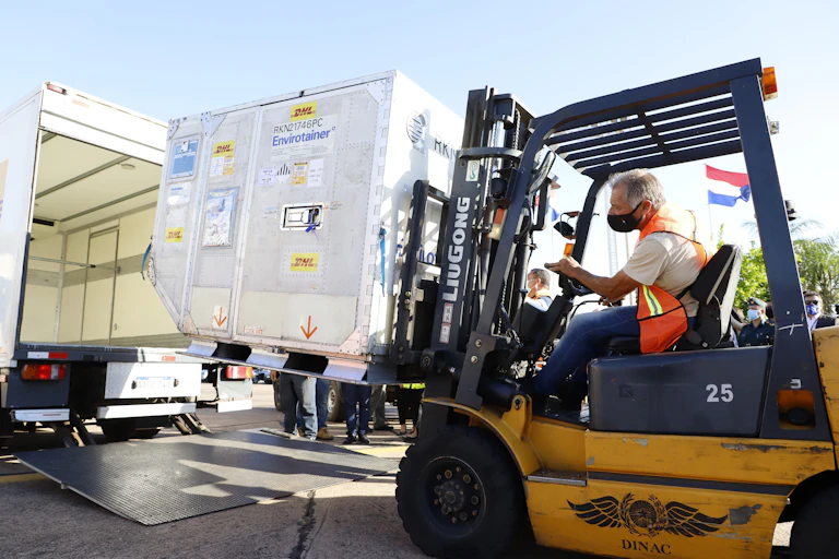 A masked man driving a forklift with a consignment of Russian Sputnik V vaccines.