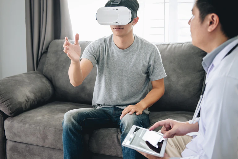 Man wearing virtual reality headset is monitored by his therapist.