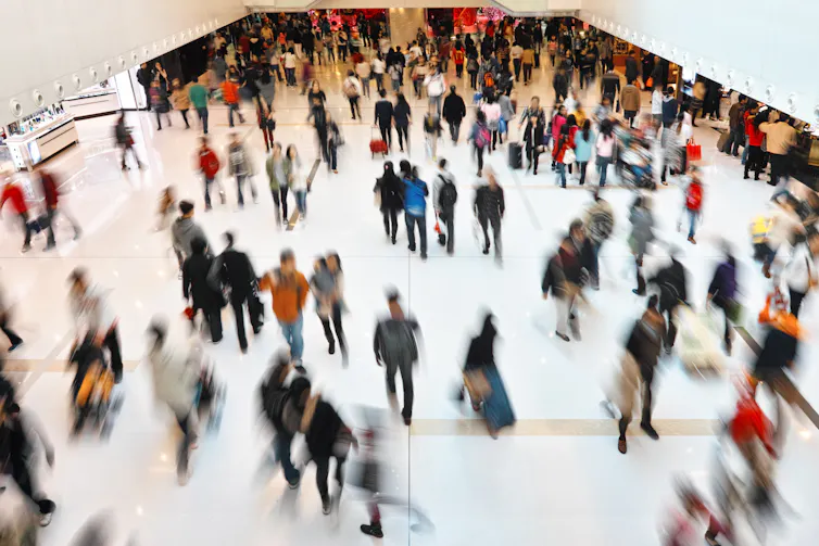 A busy shopping centre with many people walking around, some blurred