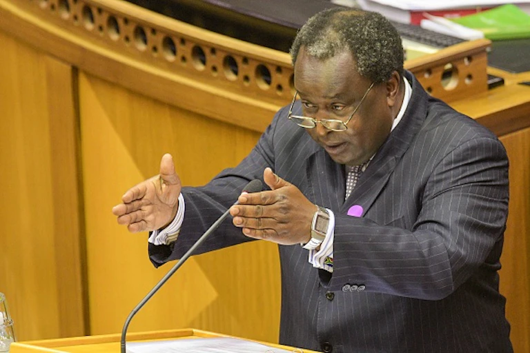Man at a podium gestures while speaking into microphone