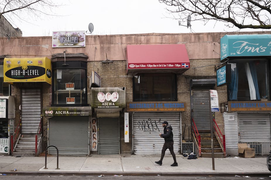 A pedestrian strolls past small businesses that are shuttered closed during the coronavirus epidemic in Brooklyn.