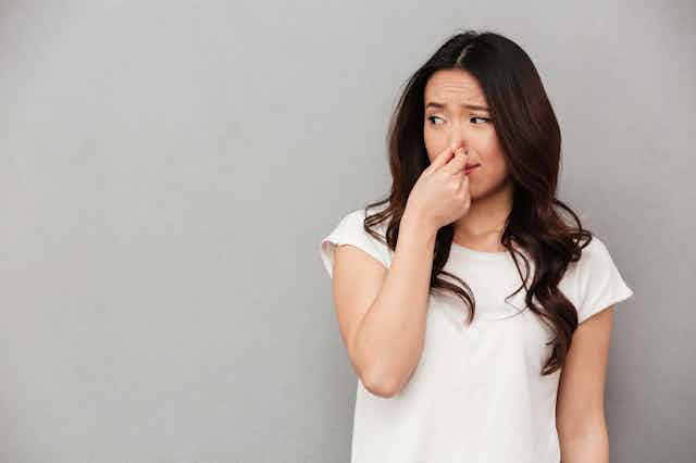 Woman holding her nose against bad smell