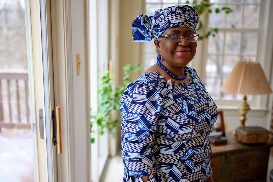Woman in print headwrap and matching dress, standing in an interior