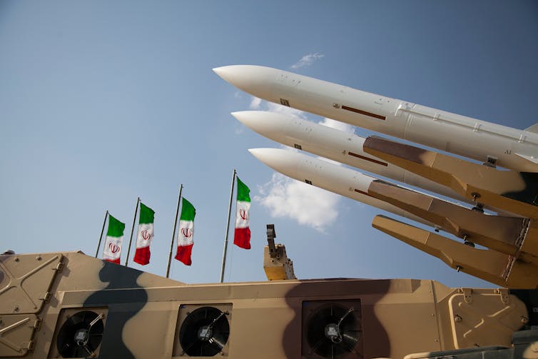 An array of missiles with Iranian flags in the background.