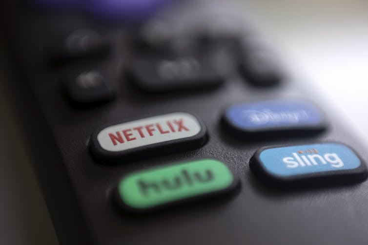 Un control remoto de televisión con un botón etiquetado como Netflix, Hulu, Disney + y Sling