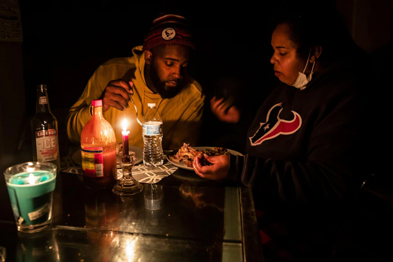 A man and woman eat dinner by candlelight