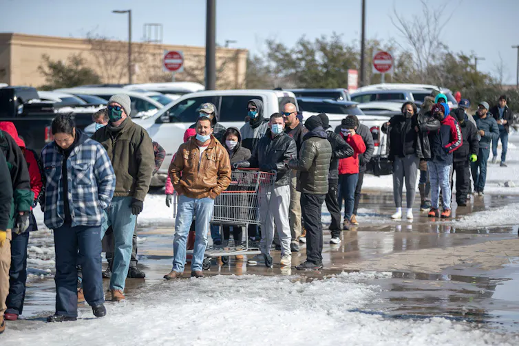 People queue up in cold car park.