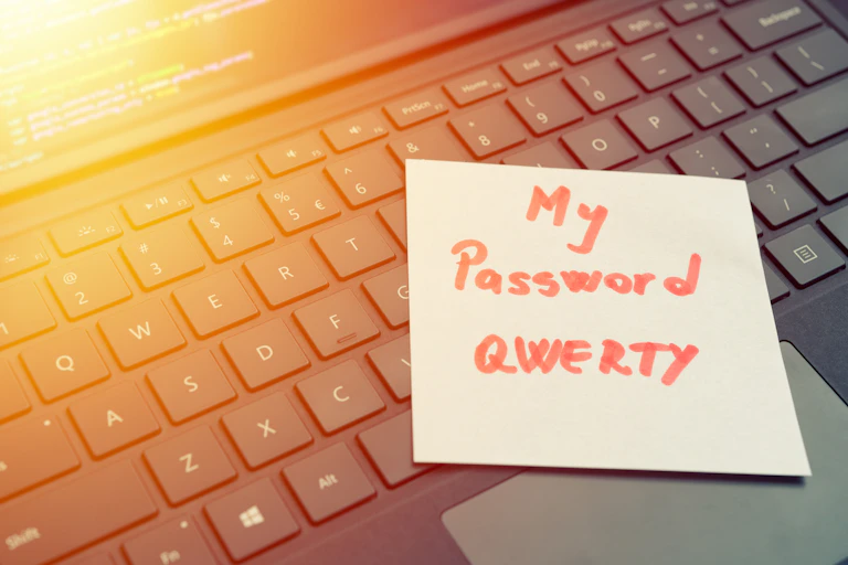 A post-it note on a computer displays a password.