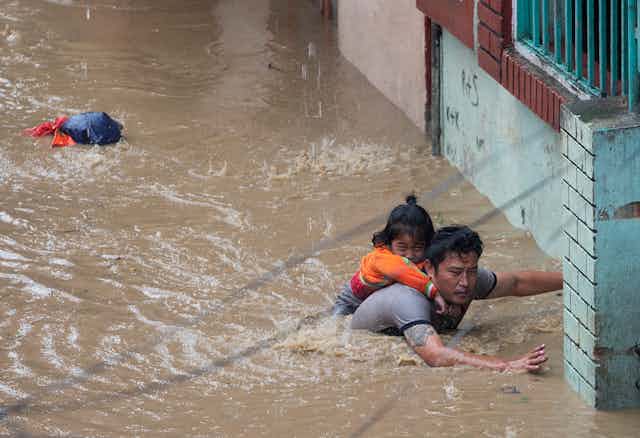 Man carries child through floodwaters in Nepal