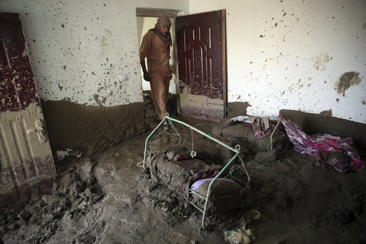 A man searches for belongings in flooded house