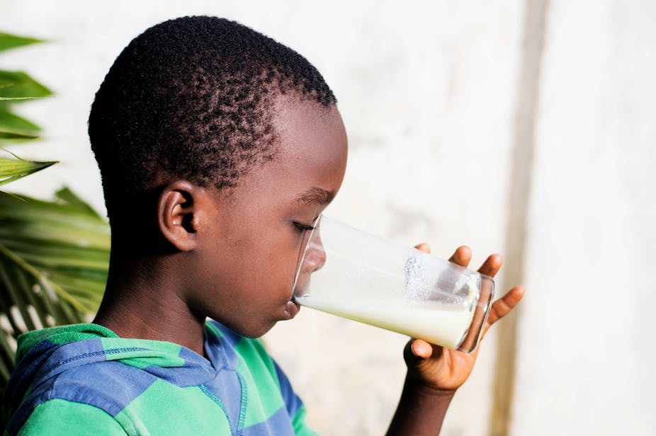 A young boy drinking milk from a glass.