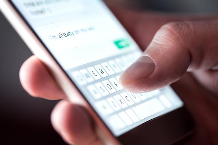 A phone screen with a thumb writing a text.