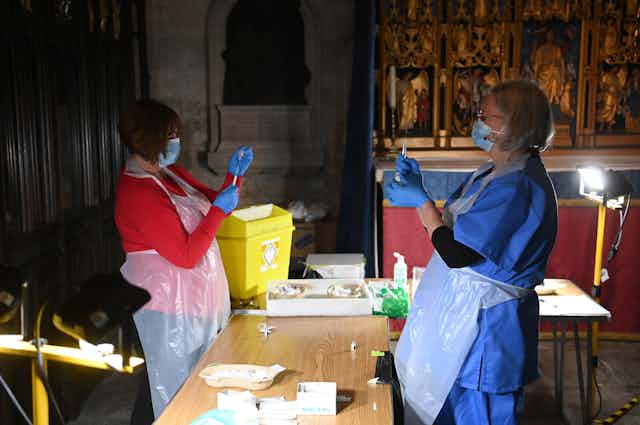 Two clinicians dose up syringes with COVID vaccines in Salisbury Cathedral, where a vaccination centre as has been set up.