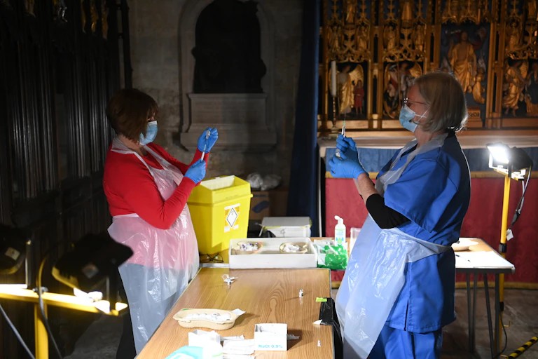 Two clinicians dose up syringes with COVID vaccines in Salisbury Cathedral, where a vaccination centre as has been set up.