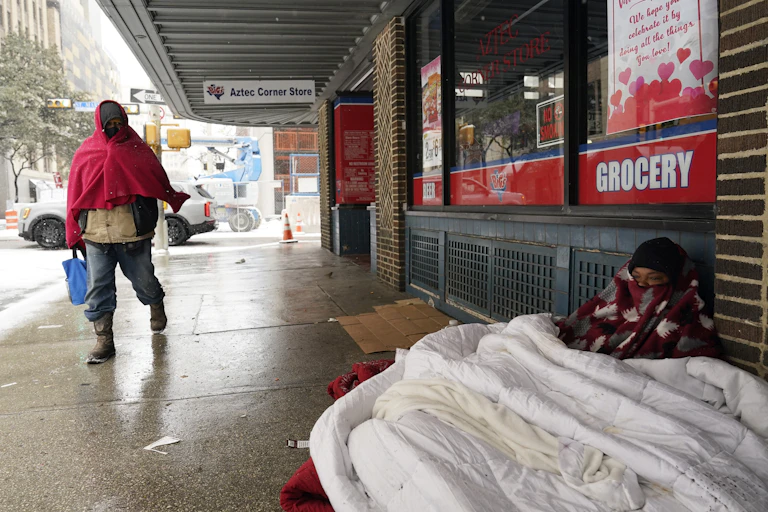 A woman living on the streets uses blankets to keep warm.