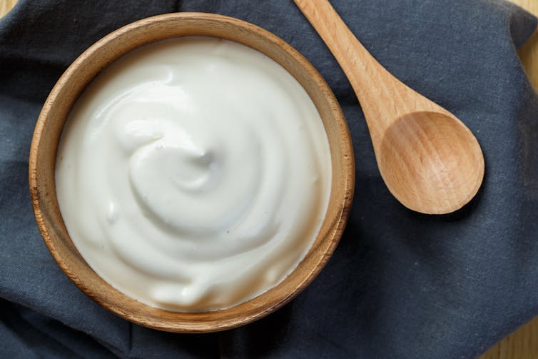 Ciotola di yogurt bianco con cucchiaio di legno.